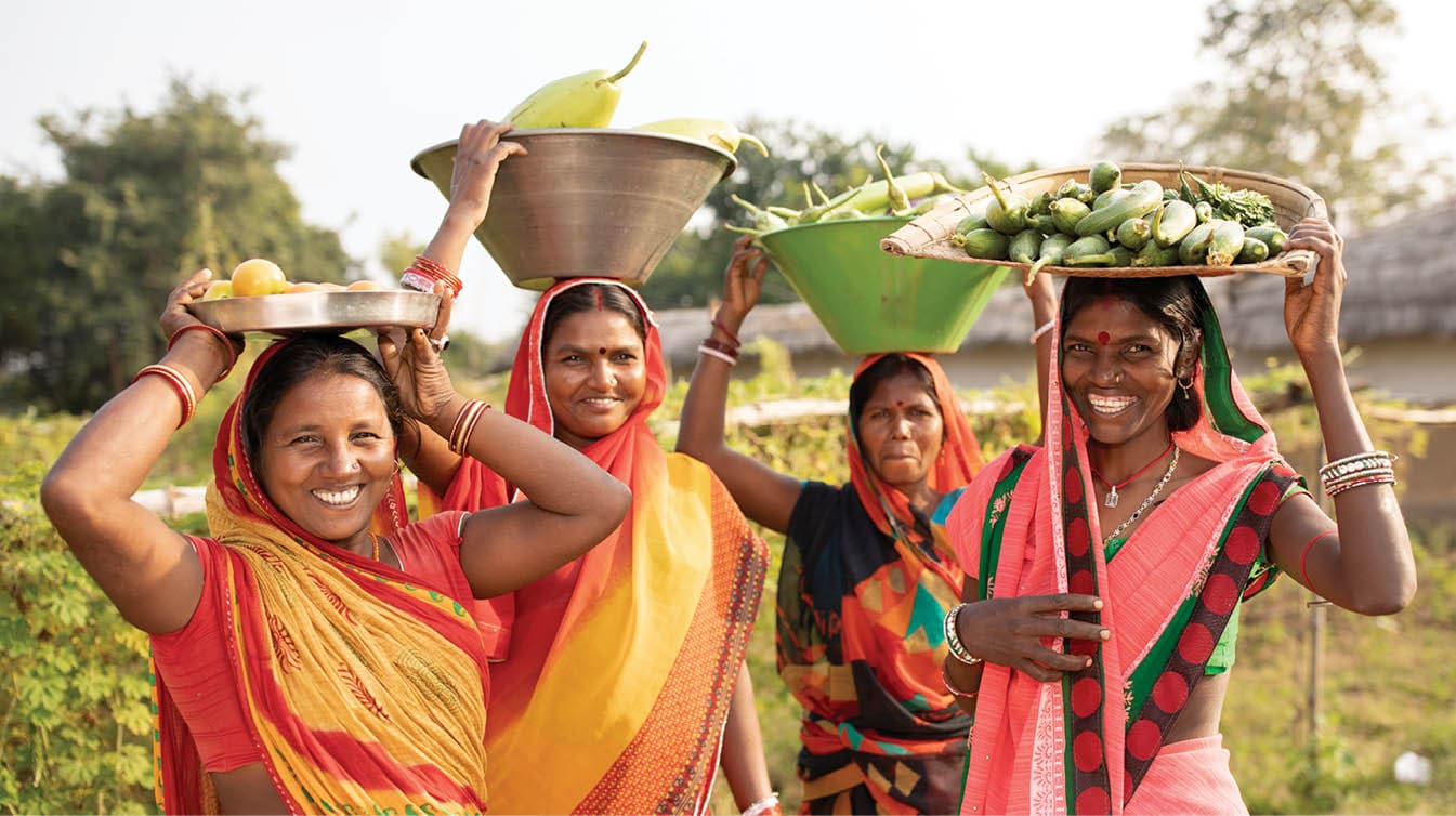 De derecha a izquierda: Chandrika Devi (35), Manti Devi (32), Nirmala Devi (32) y Manju Devi (35) traen cestas de calabazas recién cosechadas de sus granjas en Bihar, India. Estas mujeres se han empoderado y sus medios de subsistencia se han fortalecido gracias a Partnership Bihar, una iniciativa de Lutheran World Relief que aporta mejores técnicas agrícolas, semillas de alta calidad, nutrición mejorada para las familias y grupos de autoayuda de microfinanciación a las comunidades de uno de los estados más pobres de la India. Proyecto Pradan (Asistencia profesional para la acción de desarrollo) / Partnership Bihar.  21 de noviembre de 2019 - Distrito de Banka, estado de Bihar, India. Fotografía de Jake Lyell para Lutheran World Relief.
