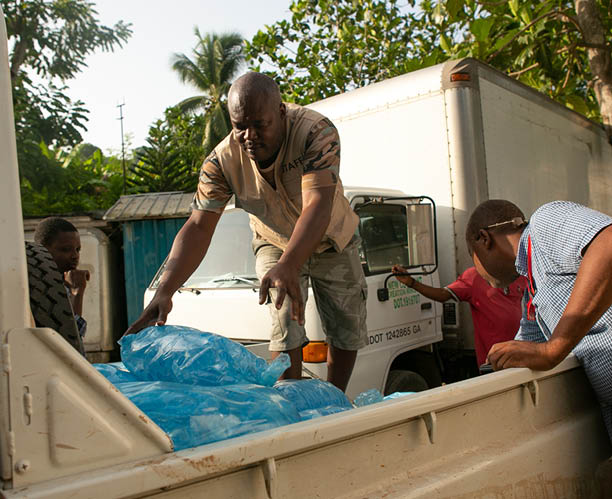 A la périphérie de Jérémie, en Haïti, des représentants de LWR Corus et de la fondation suisse HEKS EPER chargent une camionnette de sachets d'eau potable destinés aux villages touchés par le séisme dans le département de la Grand Anse, en Haïti, le 24 août 2021. Un séisme d'une magnitude de 7,2 a secoué la région dix jours plus tôt, causant d'importants dégâts dans cette zone (Photo par Allison Shelley pour LWR Corus).