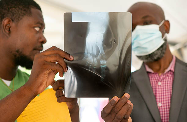 Le Dr Dummond Done Doulo, à gauche, et le directeur de l'hôpital, le Dr Pierre Robert Azor, examinent une radiographie du pied écrasé d'une victime du séisme de magnitude 7,2 qui a dévasté la région le 14 août, à l'hôpital Saint-Antoine de Jérémie, dans le département de la Grand'Anse en Haïti, le 23 août 2021 (Photo par Allison Shelley pour LWR Corus).