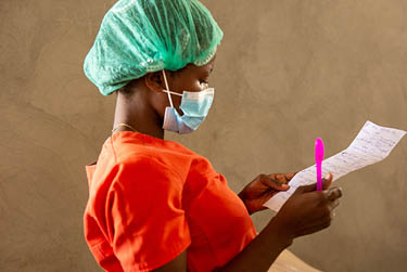 Un professionnel de la santé examine des documents dans une salle de réveil remplie de victimes du séisme à l'hôpital Saint-Antoine de Jérémie, en Haïti, le 22 août 2021, huit jours après un séisme de magnitude 7,2 qui a dévasté la région (Photo par Allison Shelley pour LWR Corus).