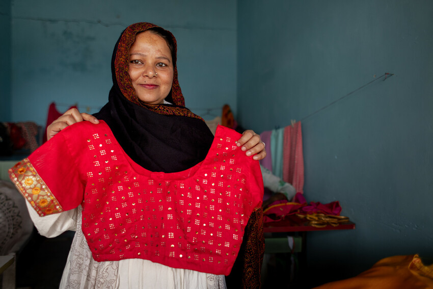 Nasrin holds up clothing she's tailored.