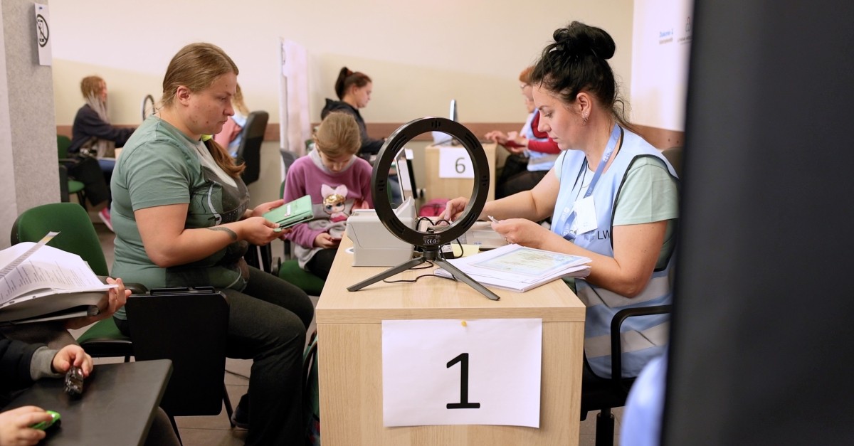 Two women sit on either side of a desk as information is collected