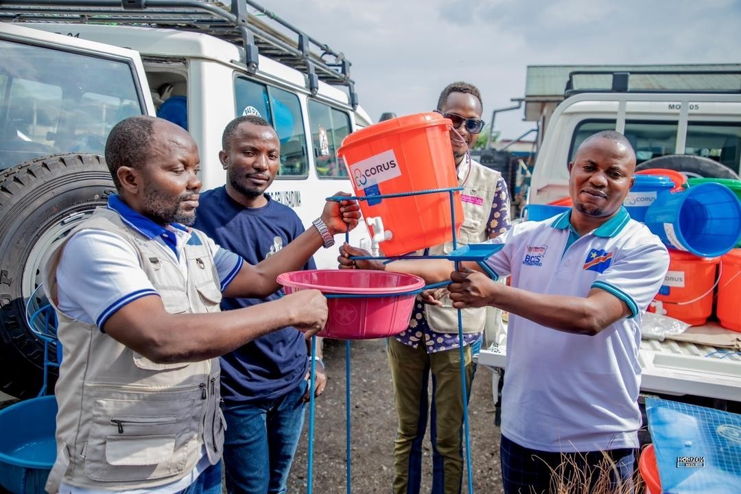 The IMA World Health team demonstrates setting up and distributes handwashing stations in a temporary IDP shelter site in Goma