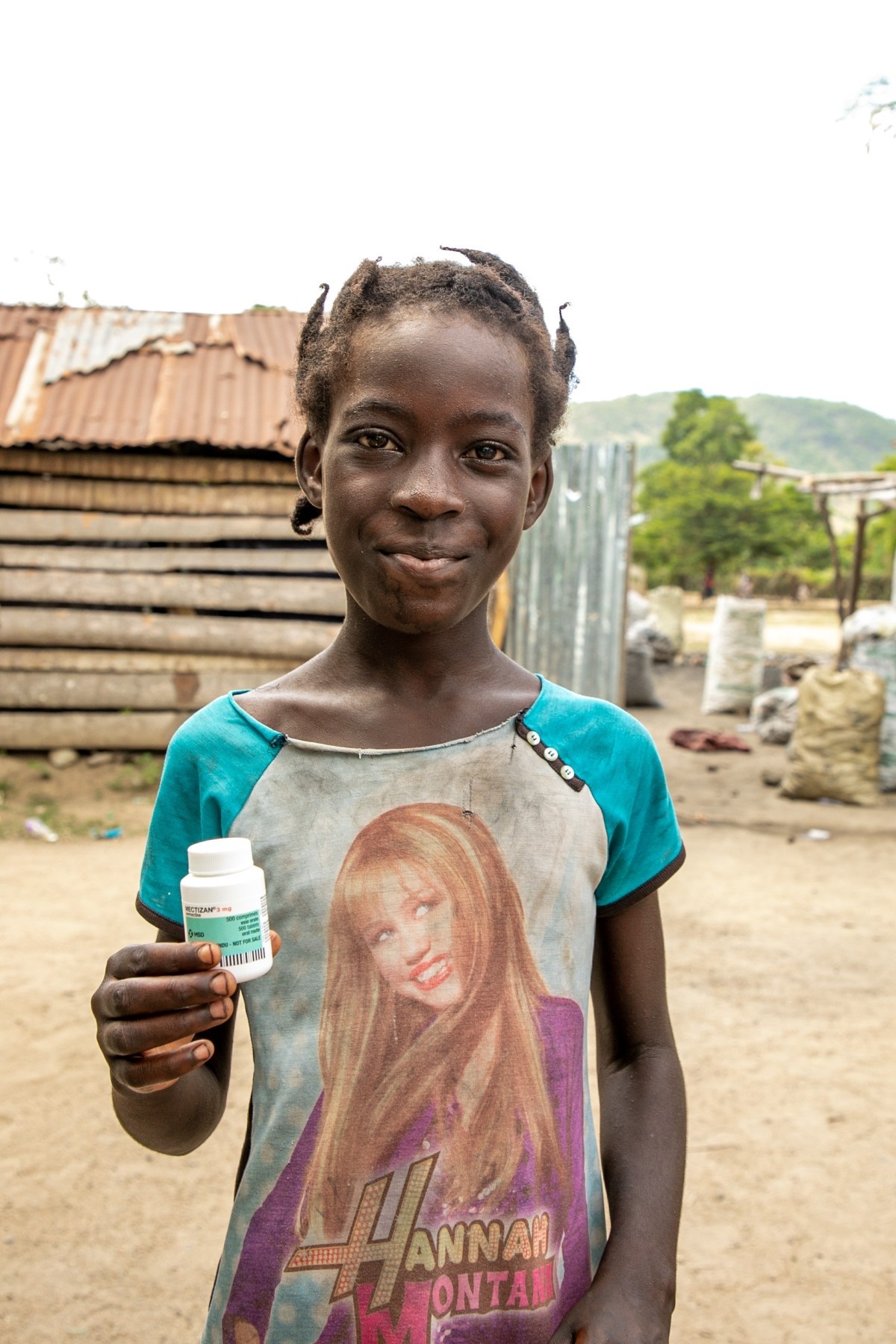 A child in Haiti holds the medicine she just took to prevent an NTD