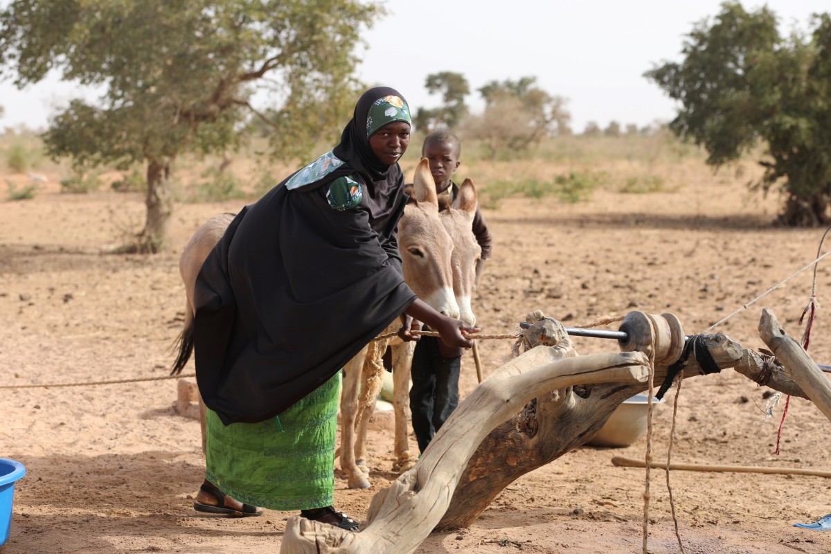 A woman pulls up water from a well