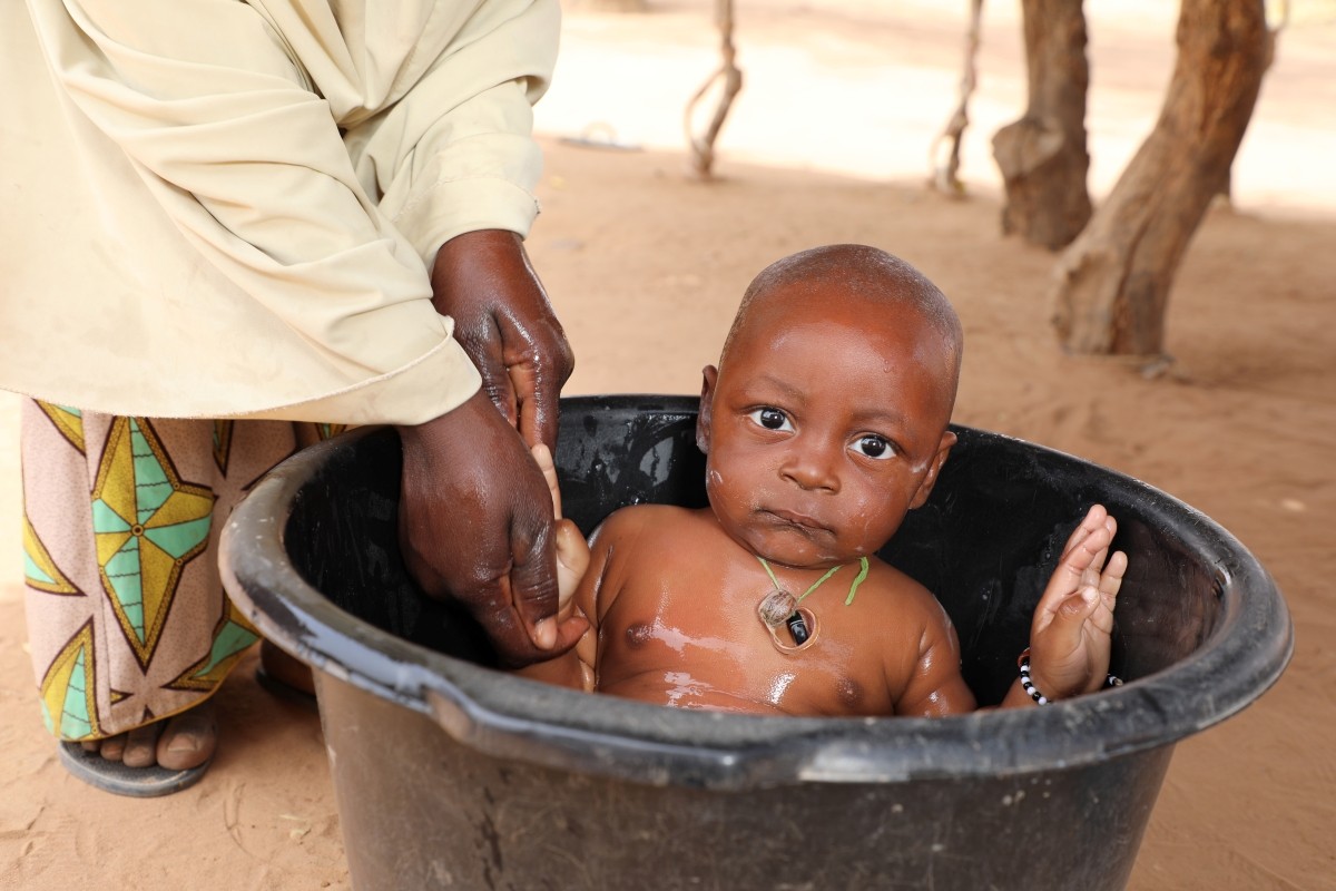 A baby is being bathed in a bucket