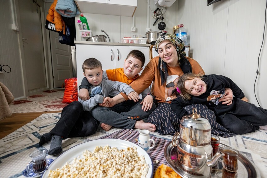 Çağla sits on the kitchen floor with three of her four children, where the family gathers to share their meals, as there's no space for a dining table.