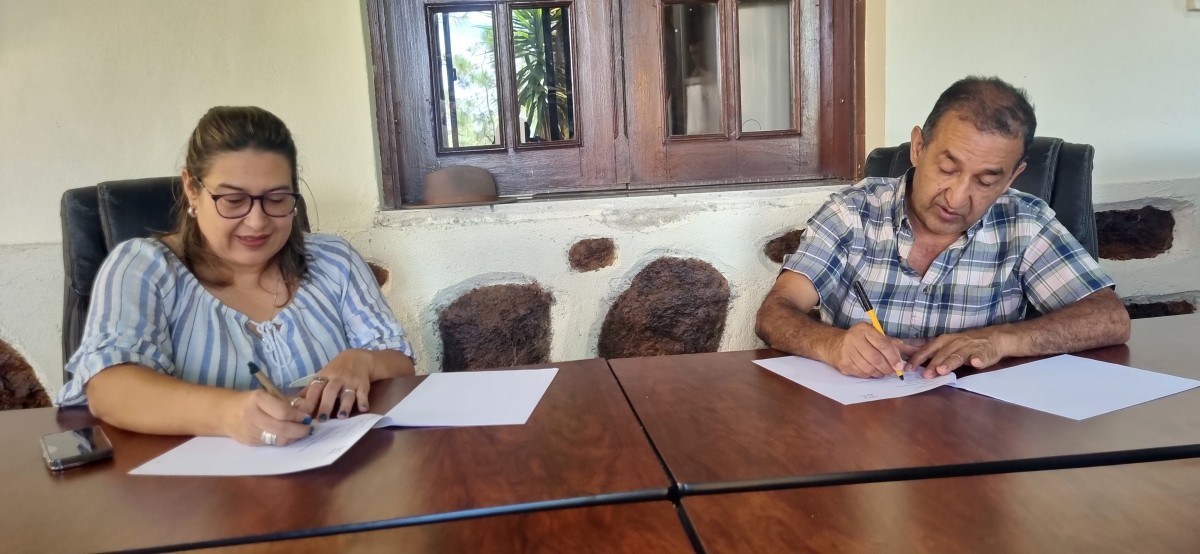 Dos personas firman documentos en un mostrador