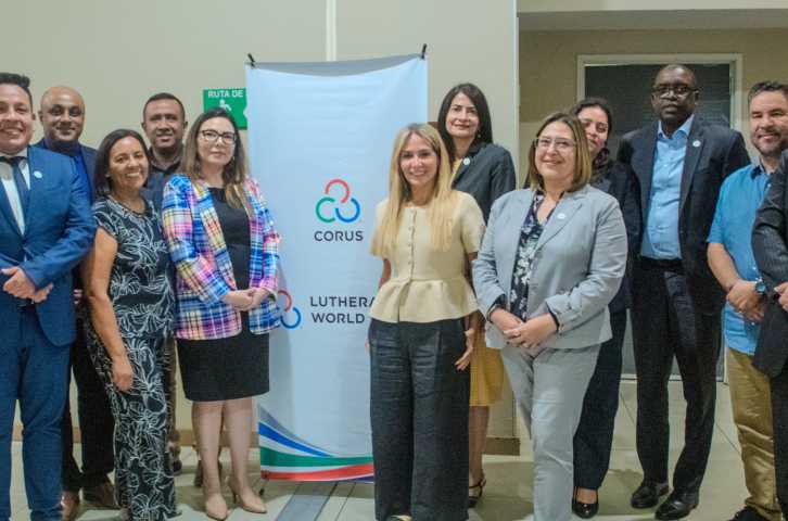 Un groupe de membres de l'équipe Corus devant une bannière Corus