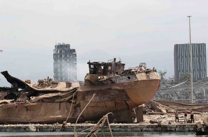 Des personnes se tiennent près de l'épave d'un navire sur le site dévasté de l'explosion dans le port de Beyrouth, au Liban, jeudi 6 août 2020. (AP Photo/Thibault Camus, Pool)