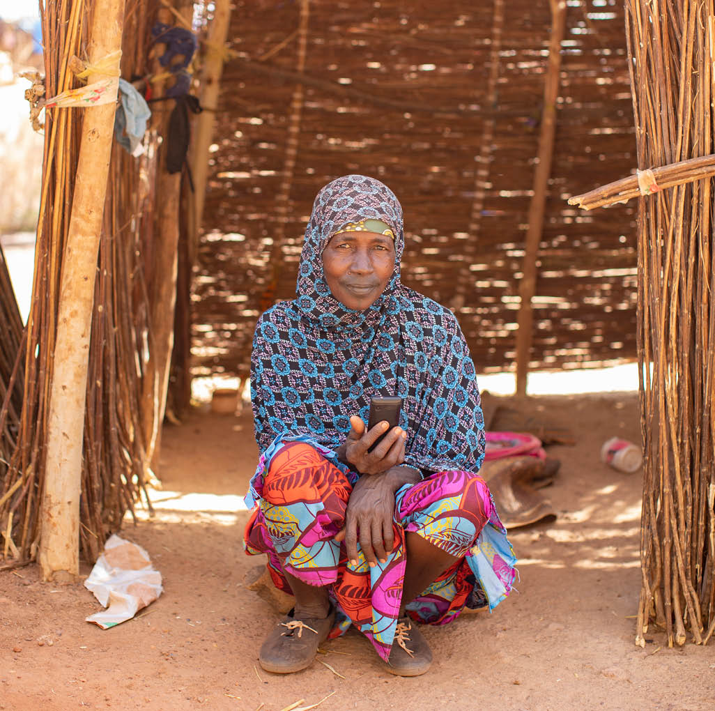 Senou Camp sits on the southern edge of Bamako, Mali s capital city  It is one of eight such informal camps around the city and, by itself, is home to 223 families and just over 1,000 IDPs  The families living here have fled violence and insurrection in the north and central parts of the country  Because most of them have no means of income or regular food source, hunger is a daily challenge and malnutrition among its population remains rife    Here, a woman sits in her makeshift shelter holding her mobile phone   Sahel 2021 Crisis; Senou, Mali  Feb 24, 2021  Photo by Jake Lyell 